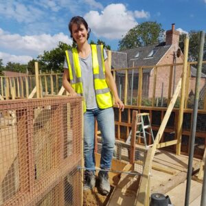 Nicola surrounded by wooden frames on a house building site
